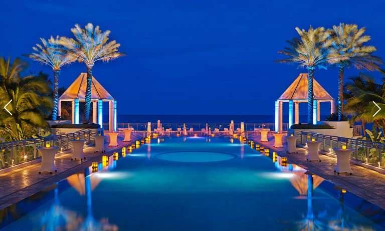 a pool with palm trees and a gazebo at night