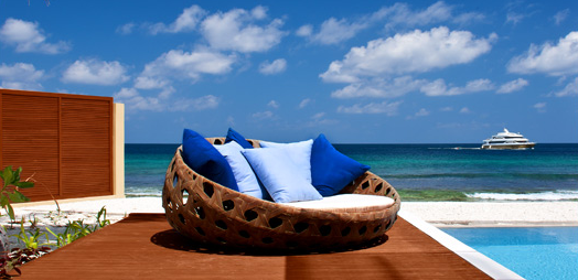 a wicker chair with blue pillows on a beach