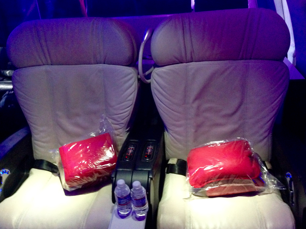 a seat with red pillows and a drink on it
