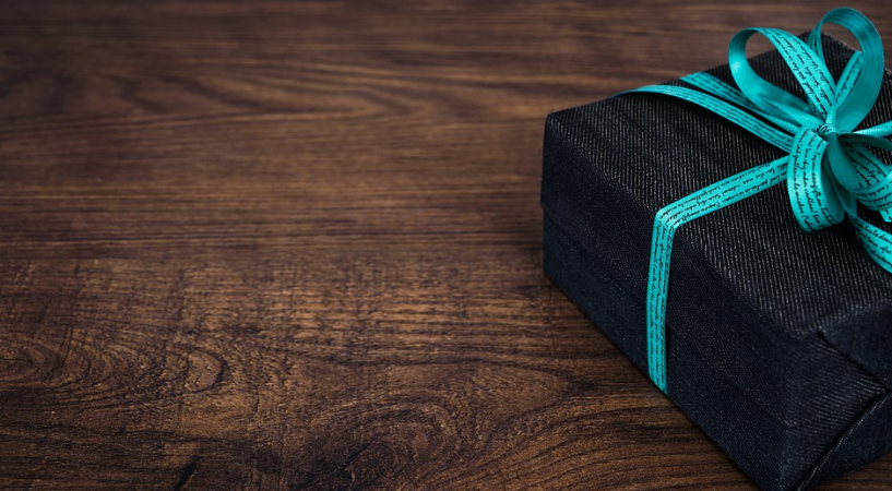 a black box with a blue ribbon on a wooden surface