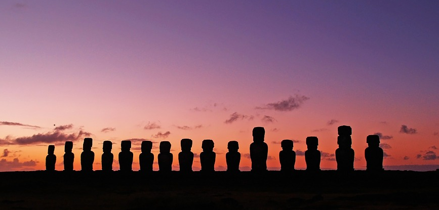 a row of statues in front of a sunset