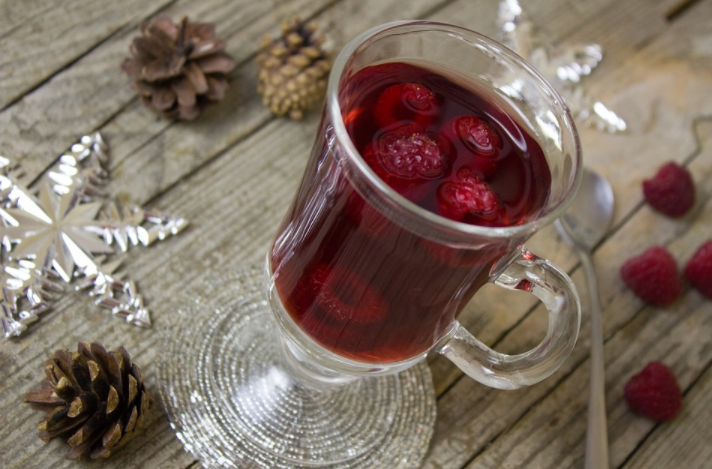 a glass cup of red liquid with berries