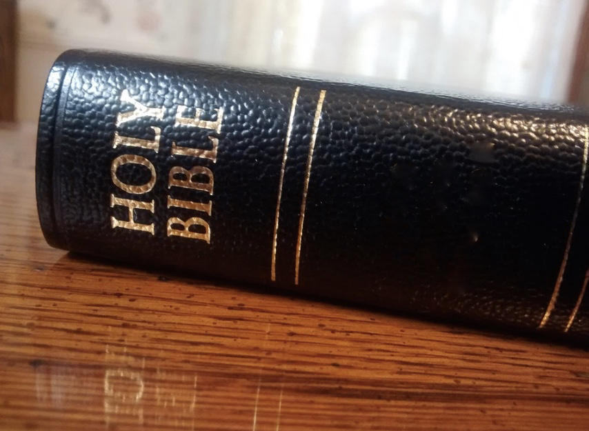 a black leather bible on a wood surface
