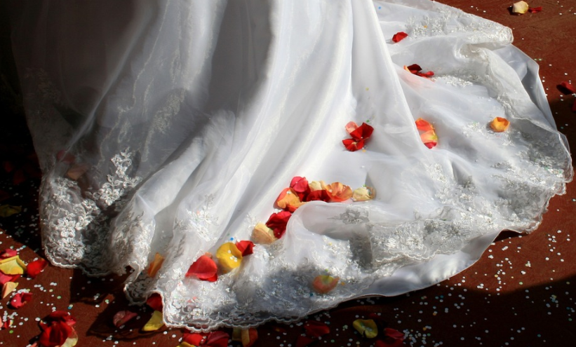 a white wedding dress with red and yellow petals