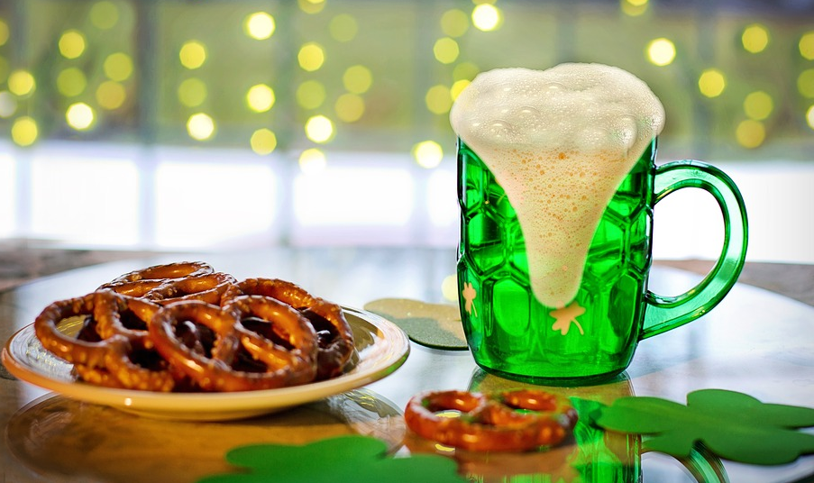 a green mug of beer and a plate of pretzels