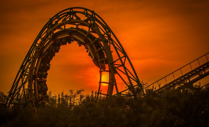 a roller coaster with trees and a sunset