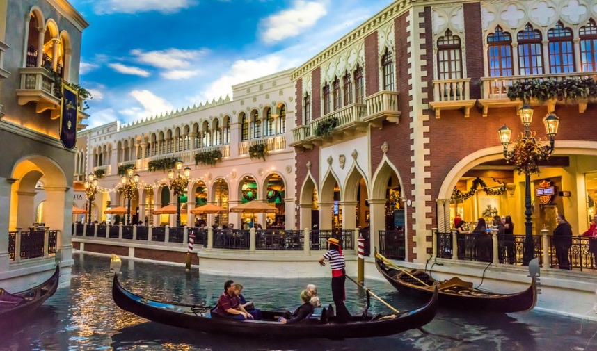 a gondola in a canal with people in it with The Venetian Las Vegas in the background