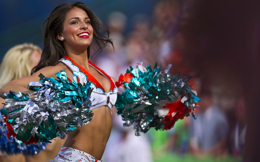 a cheerleader in a white and blue uniform with pom poms